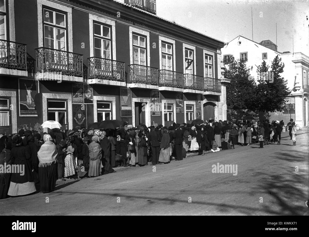 In Lissabon im Jahr 1918, auf der Rua da Junqueira, wird eine Menschenmenge auf die Eröffnung eines staatlich regulierten Lebensmittellagers („armazém regulador de precos“), das geschaffen wurde, um die Lebensmittelspekulation im Nachkriegs-Portugal zu bekämpfen, gewartet. Stockfoto