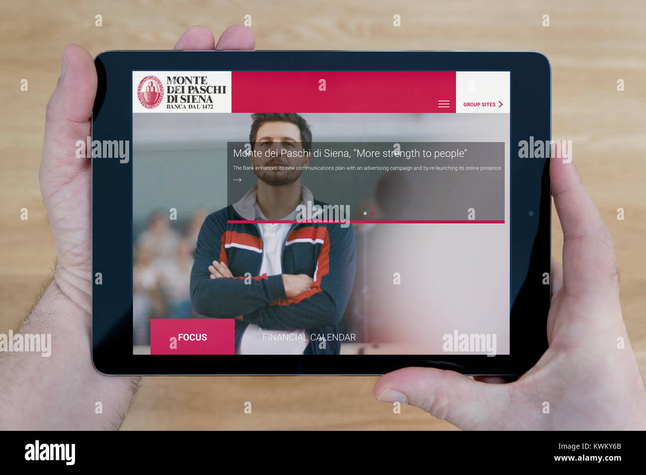 Ein Mann sieht die BMPS (Banca Monte dei Paschi di Siena) Website auf seinem iPad Tablet Vorrichtung, die auf einer hölzernen Tisch top Hintergrund (nur redaktionelle Nutzung) Stockfoto