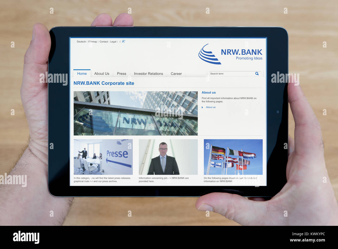 Ein Mann schaut auf die NRW.BANK Website auf seinem iPad Tablet Vorrichtung, die auf einer hölzernen Tisch top Hintergrund (nur redaktionelle Nutzung) Stockfoto