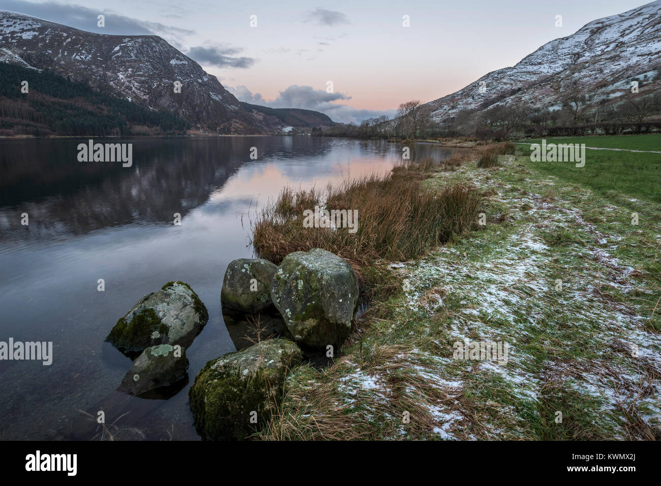 Schönen Sonnenaufgang Landschaft Bild im Winter von Llyn Cwellyn in Snowdonia National Park mit Schnee bedeckte Berge im Hintergrund Stockfoto