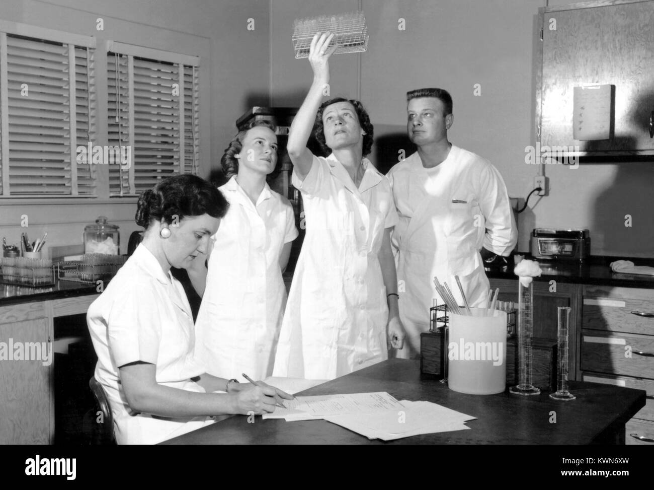 Männliche und weibliche Forscher in der Viralen des CDC und rickettsial Krankheit Lab, Teil der Geschlechtskrankheit Division der US-amerikanischen Public Health Service, interpretieren die Ergebnisse einer Komplementbindungsreaktion, 1957 ergänzen. Mit freundlicher CDC. Stockfoto