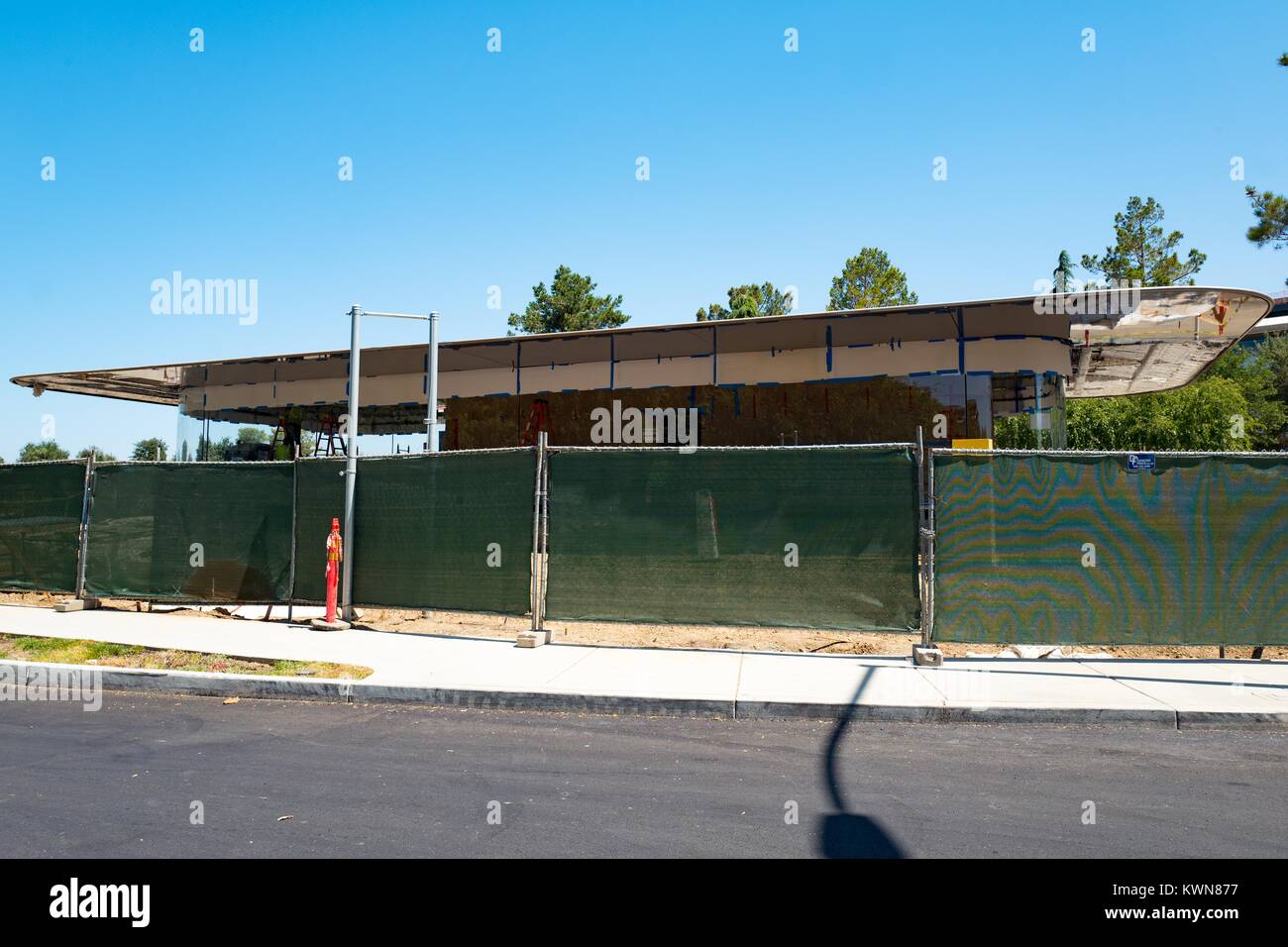 Eine teilweise konstruierten Gebäude sichtbar ist hinter einem Bauzaun auf Pruneride Allee am Apple Park, umgangssprachlich als "Raumschiff", die neue Zentrale von Apple Inc. in den Silicon Valley Stadt Cupertino, Kalifornien, 25. Juli 2017 bekannt. Stockfoto
