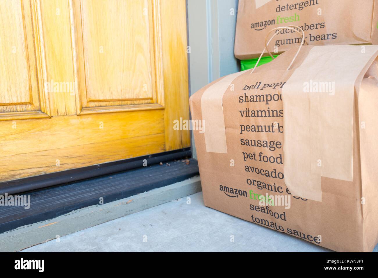 Braunes Papier Tragetasche für Amazon frische Lebensmittel Lieferservice,  mit Amazon Logo und Text Liste der Lebensmittel, die mit dem Service  bestellt werden kann, vor der Tür eines Vorstadthaus in der San Francisco