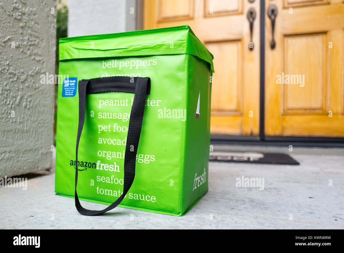 Grüne cold pack Tasche für Amazon frische Lebensmittel Lieferservice, mit  Amazon Logo und Text Liste der Lebensmittel, die mit dem Service bestellt  werden kann, vor der Tür eines Vorstadthaus in der San