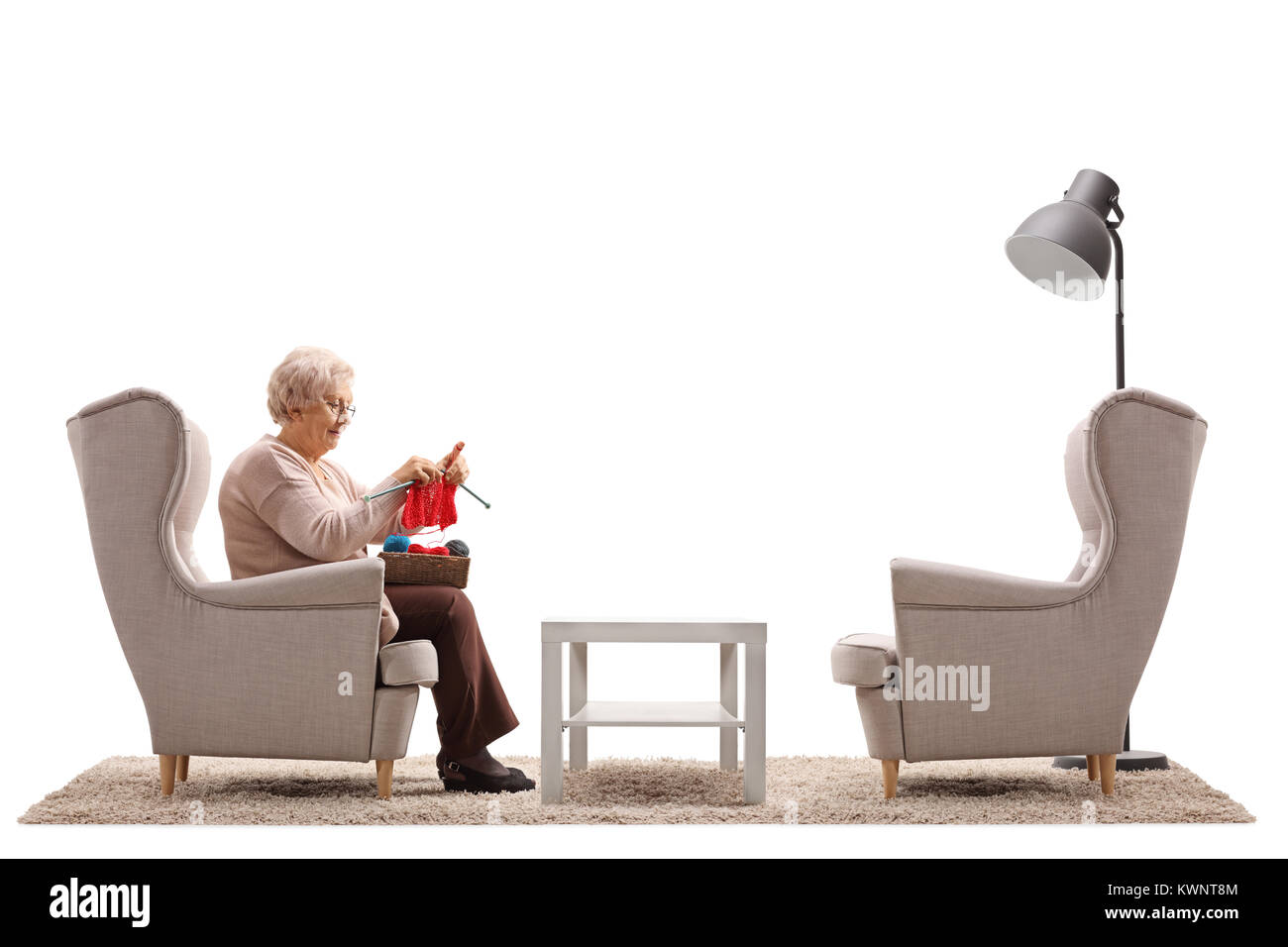 Einsame alte Frau im Sessel sitzen und stricken auf weißem Hintergrund Stockfoto