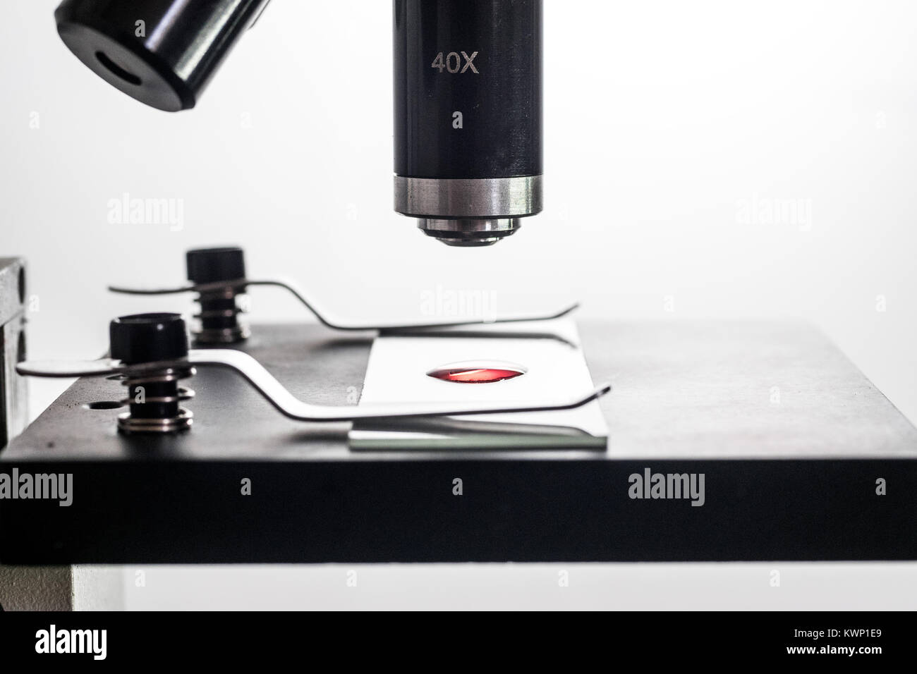Mikroskop und Mikroskop Objektträger closeup, hinterleuchtet, Makro, mit einem kleinen roten Blutkörperchen Substanz liquid Droplet auf dem Objektträger, weiß backgr Stockfoto