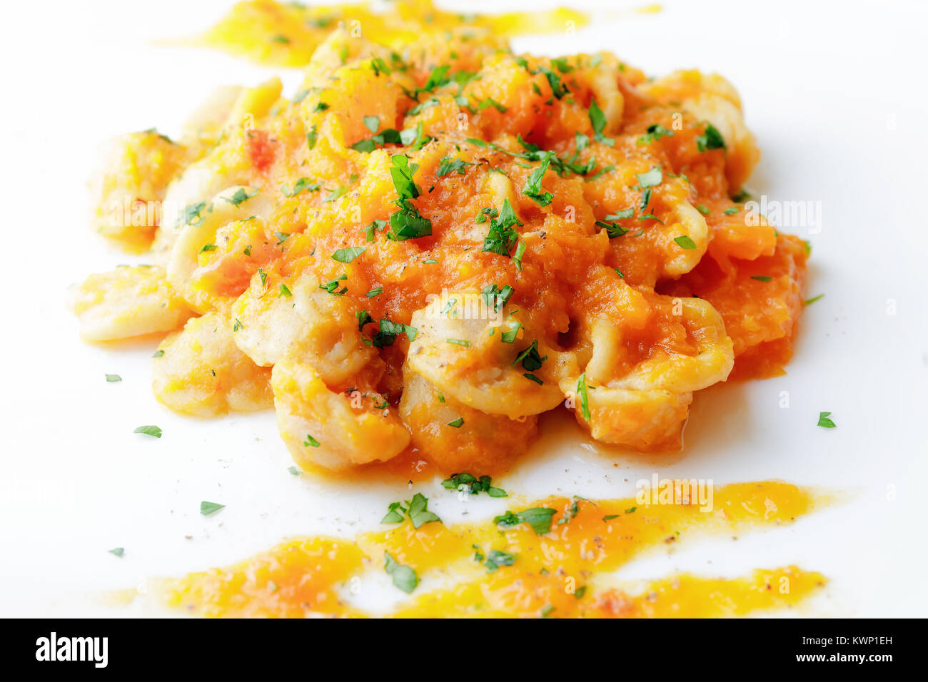 Bereit Teller Pasta mit Kürbis, Tomaten, Öl und Petersilie. Weiße Platte auf einem weißen Hintergrund. Italienische Küche. Stockfoto