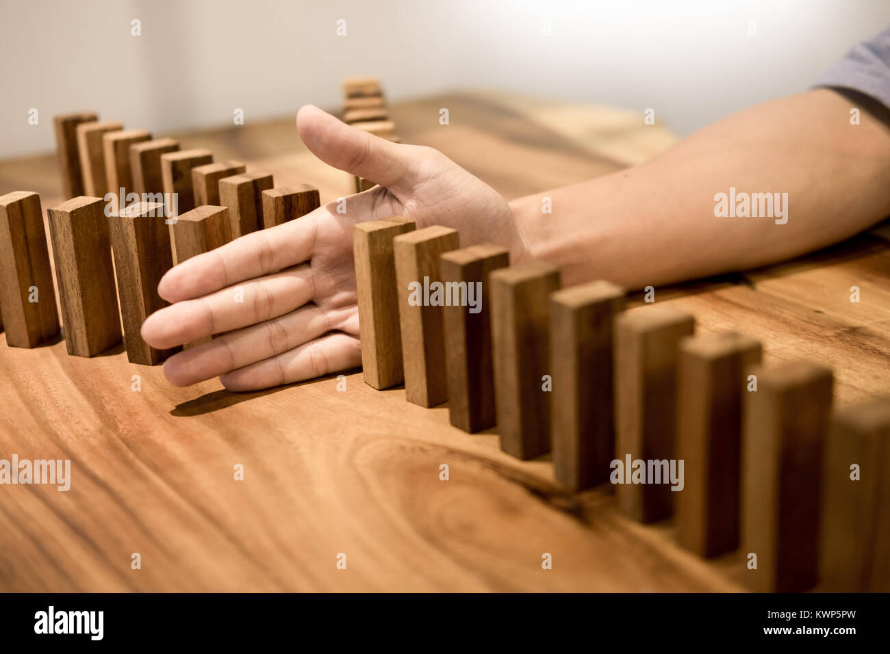 Geschäftsmann Hand zu stoppen, Dominosteine kontinuierliche gestürzt oder Risiko mit Exemplar Stockfoto