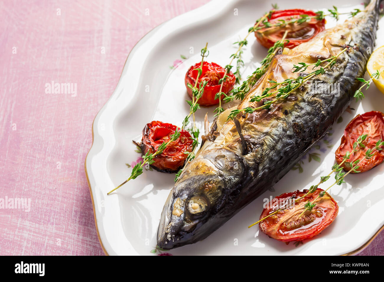 Makrele mit Tomaten und Thymian auf rosa Tabelle in vintage Platte gebacken Stockfoto