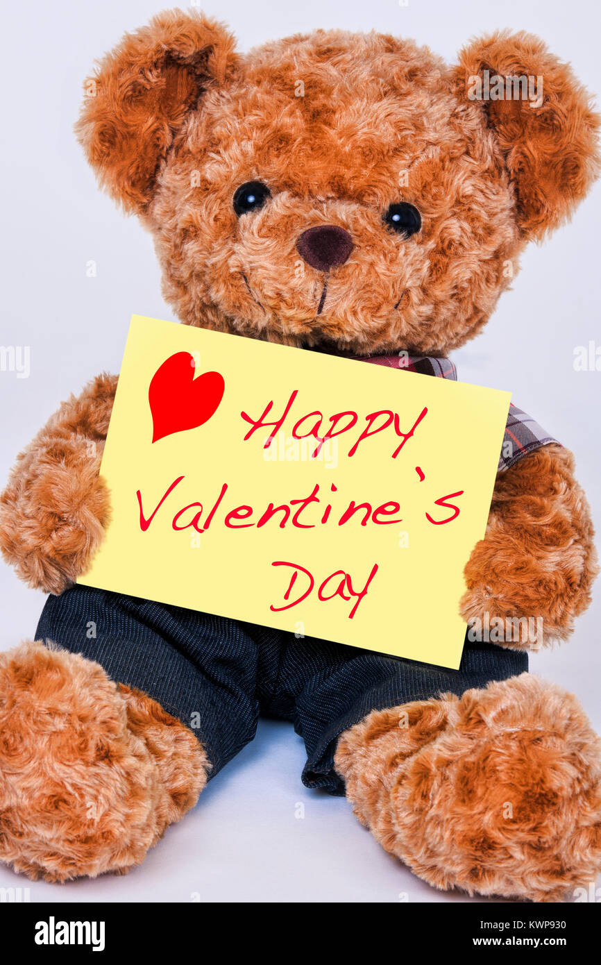Eine niedliche Teddybär Holding ein gelbes Schild mit der Aufschrift Happy Valentine's Day auf weißem Hintergrund Stockfoto