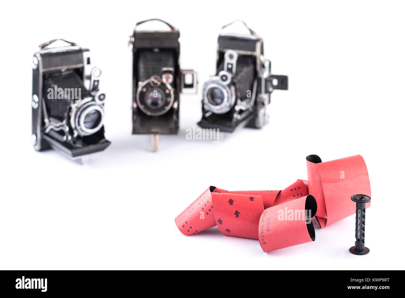 Retro 120 Film mit Kunststoff Schieber für mittlere Format retro Kameras auf weißem Hintergrund mit Schatten, drei blurry klassische Kameras auf Hintergrund, auctio Stockfoto