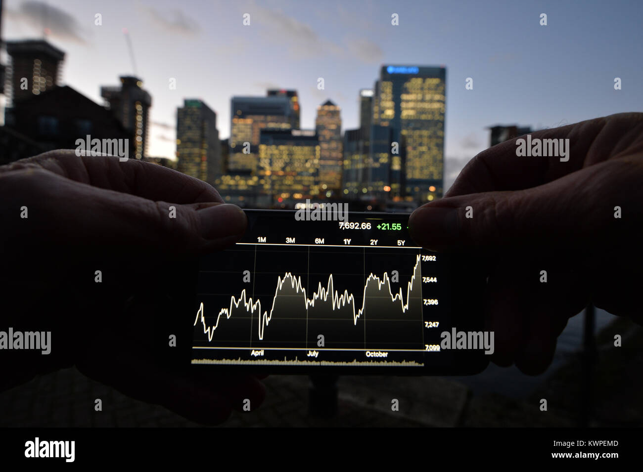 Eine Person, die Aussicht auf ein Iphone, mit der Londoner Canary Wharf im Hintergrund. Stockfoto