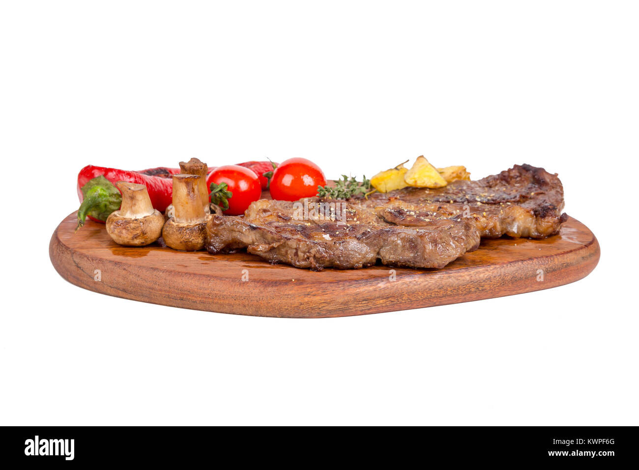 Detaillierte Ansicht von lecker lecker Gegrilltes Steak auf Holzplatte mit Kartoffel, Tomate und Paprika diente, auf weißem Hintergrund. Stockfoto