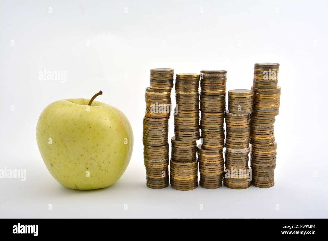 Gelber Apfel mit Münzen auf weißem Hintergrund Stockfoto