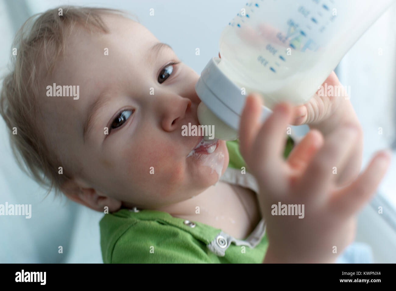 Funny baby drinking from bottle Fotos und Bildmaterial in hoher