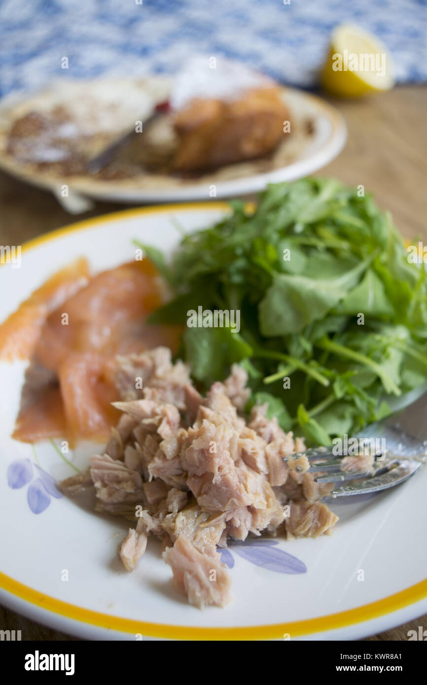 Konserven mit Thunfisch in Olivenöl mit grünem Salat serviert. Stockfoto