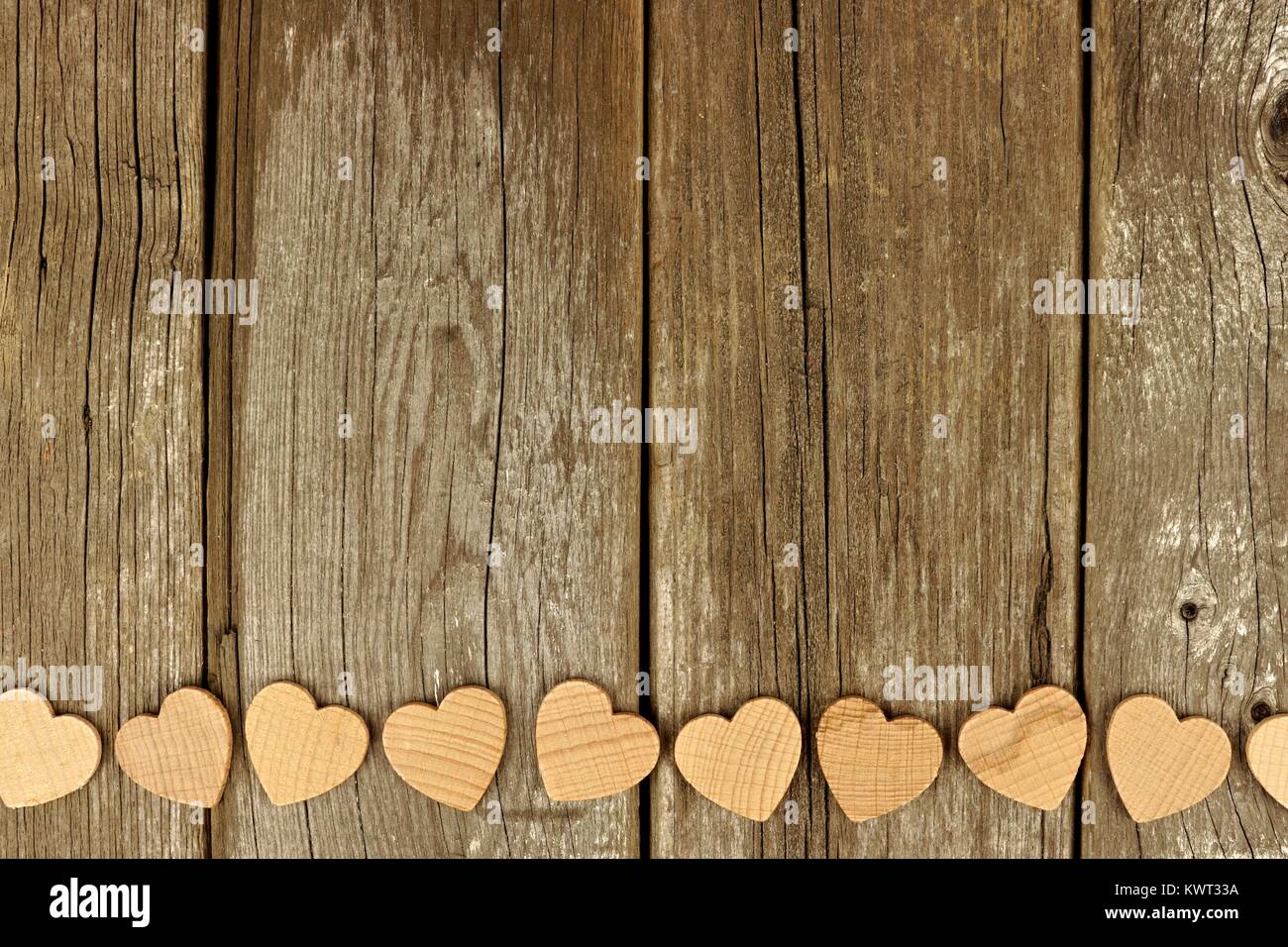 Valentines Tag Holz- Herzen bilden einen unteren Rand auf einer rustikalen, mit Holz Hintergrund Stockfoto