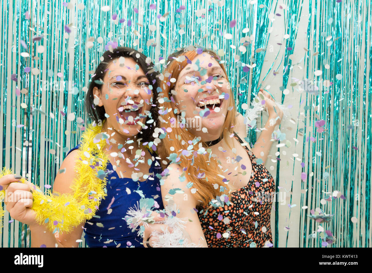 Zwei Frauen, eine Kaukasische und eine orientalische, Feiern Karneval in Brasilien. Viel Freude mit dem Regen aus Konfetti. Die Mädchen sind euphorisch. Stockfoto