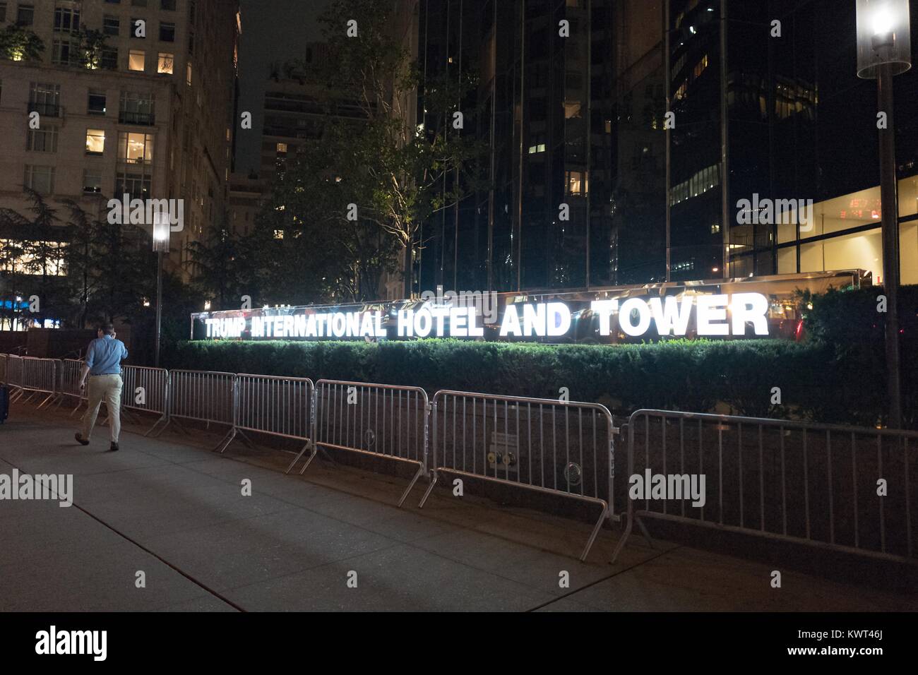 Ein Mann hinter Barrikaden in der Nacht außerhalb der Trump International Hotel and Tower am Columbus Circle in Manhattan, New York City, New York in der Nacht, mit beleuchteten Zeichen sichtbar, 14. September 2017. () Stockfoto
