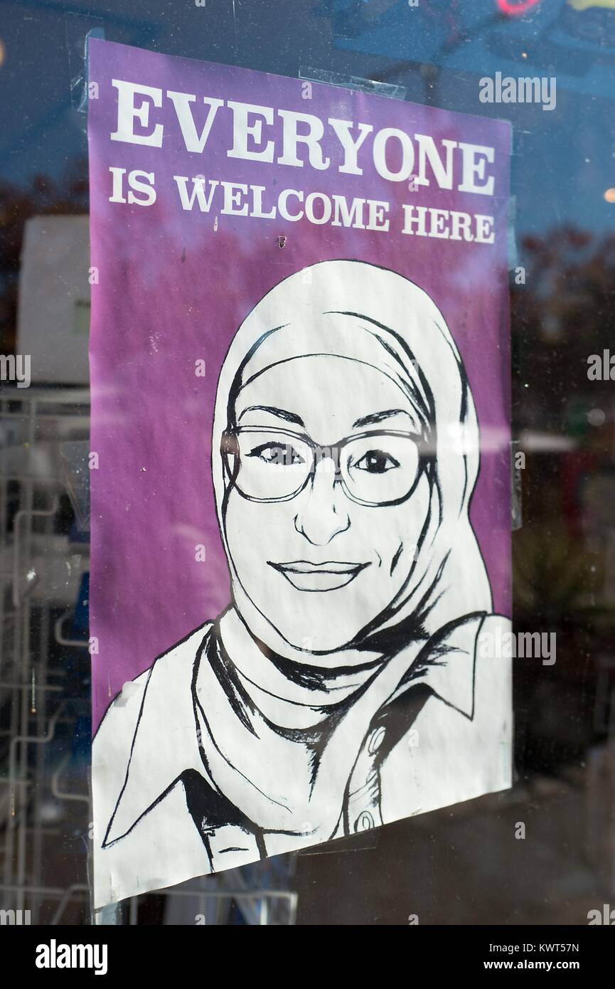 Zeichen in einem Schaufenster in der Gourmet Ghetto (Norden Shattuck) Nachbarschaft von Berkeley, Kalifornien lesen "Jeder ist hier Willkommen" und ein Bild mit einem lächelnden muslimischen Frau in einer Burka Kopftuch, Teil einer Stadt - LED-Antwort auf 'alt Rechts "Organisationen" "marxistischen" Proteste in der Stadt, 6. Oktober 2017. () Stockfoto