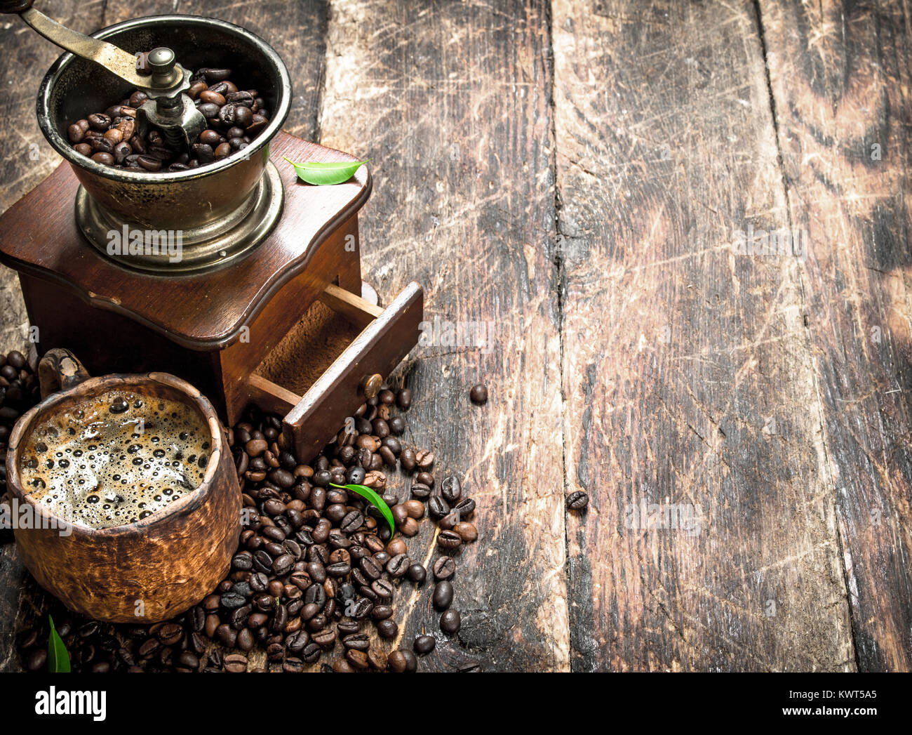 Frischer Kaffee in einem Ton Tasse mit einer alten Kaffeemühle. Auf einer hölzernen Hintergrund. Stockfoto