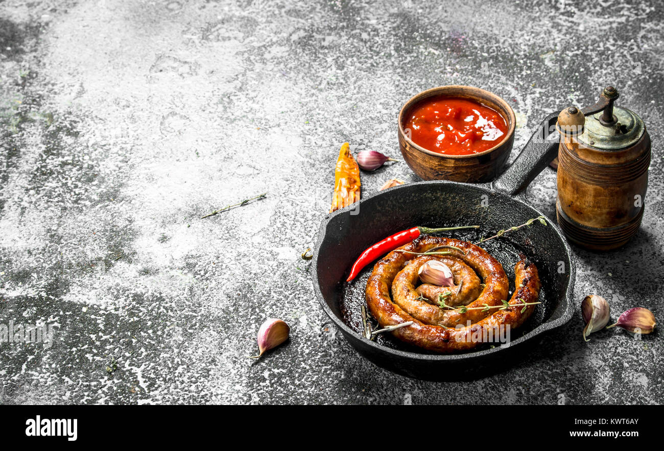 Wurst in einer Pfanne mit Peperoni, Knoblauch und Soße. Auf einem ...