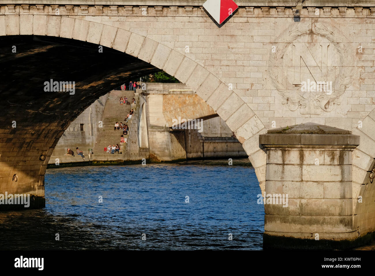 Anzeigen unter der Petit Pont auf der Pont au Double und Leute sitzen auf der Treppe hinunter zur Seine, Paris, Frankreich Stockfoto