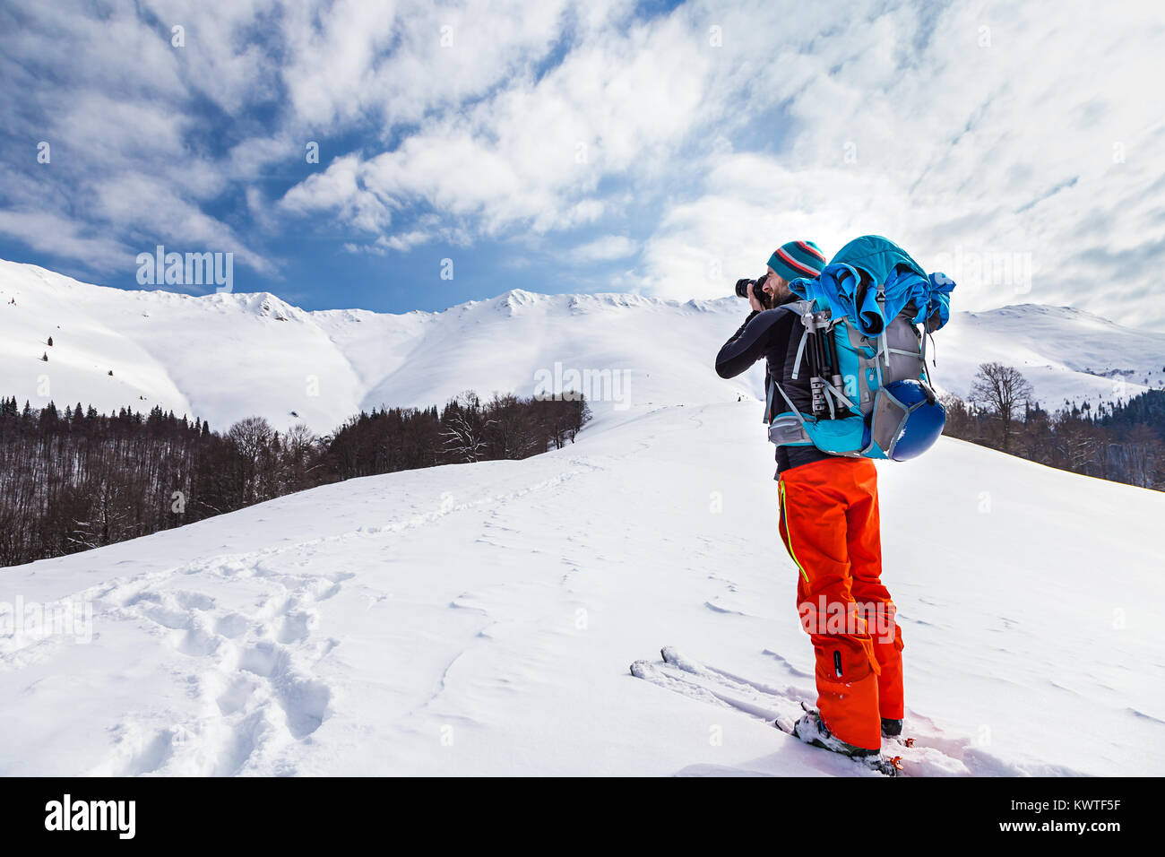 Jungen kaukasischen Mann Fotograf Bilder sprechen während backcountry Skiing an einem schönen sonnigen Tag mit frischem Schnee Stockfoto