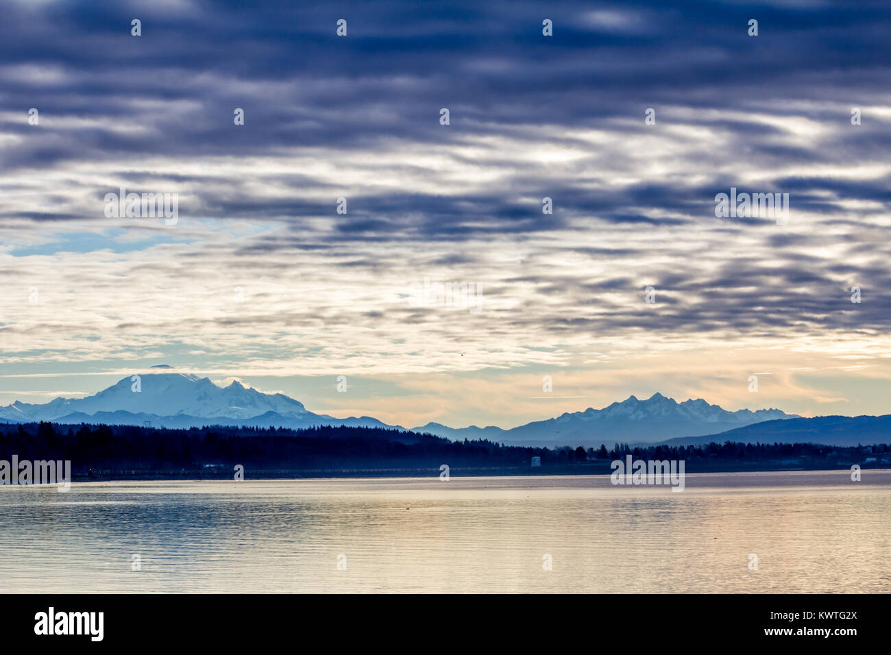 Kalter Wintermorgen. Wolken hinzufügen Drama zu Landschaft der Semiahmoo Bay und die schneebedeckten Berge von North Cascades. Weiß Frieden Bogen überspannt. Stockfoto