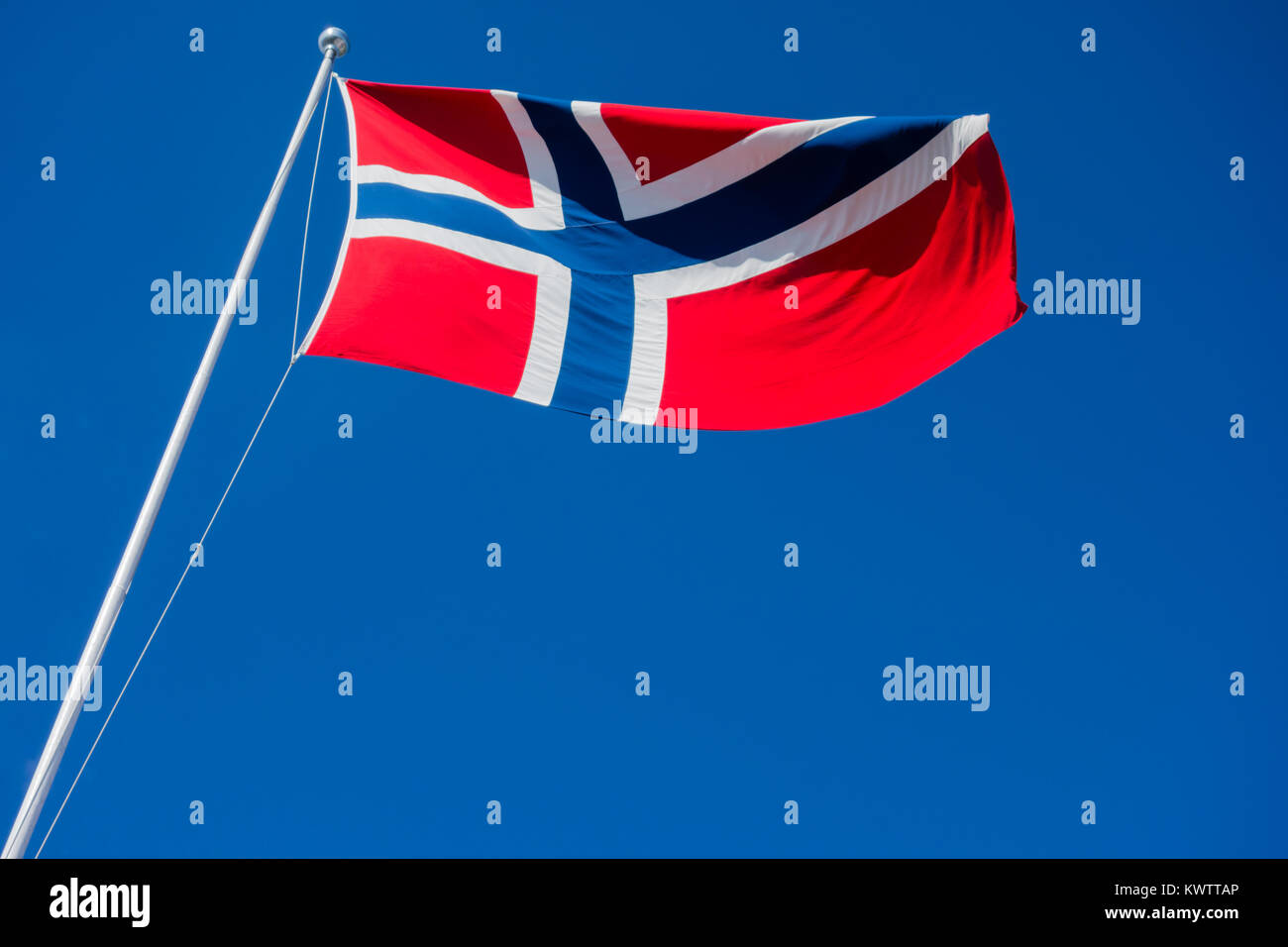 Flagge Norwegen auf Pole flattern im Wind gegen den klaren blauen Himmel. Stockfoto