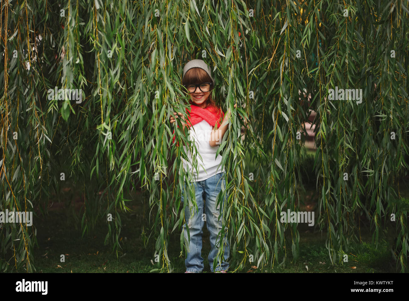 Wenig glücklich Mädchen versteckt sich in der Willow Laub Stockfoto