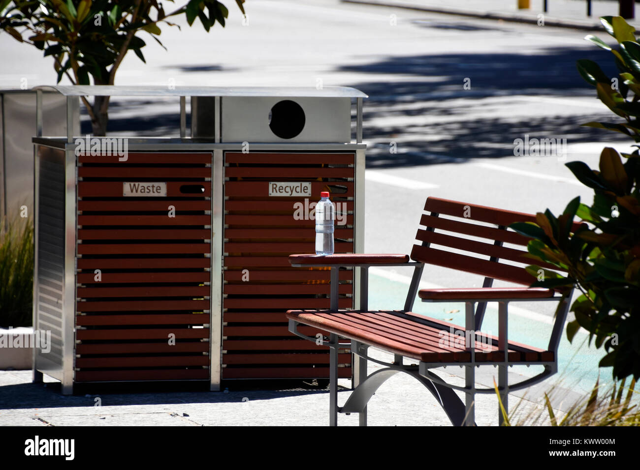 Weggeworfene Wasserflasche vergessen, neben Fach- und recyceln Punkt auf einer Parkbank Stockfoto