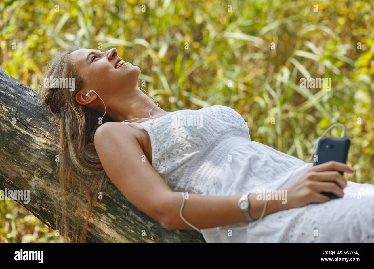 Schöne junge Frau mit Kopfhörern entspannt auf Natur Stockfoto