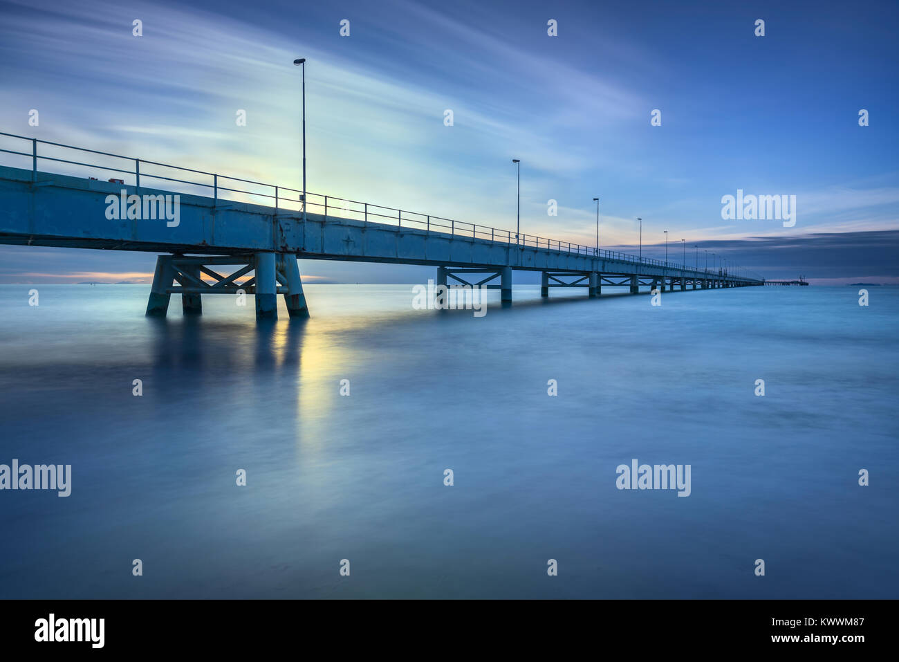 Industrielle Pier auf den Meereshorizont. Seitenansicht. Langzeitbelichtung Fotografie an einem bewölkten Tag. Stockfoto