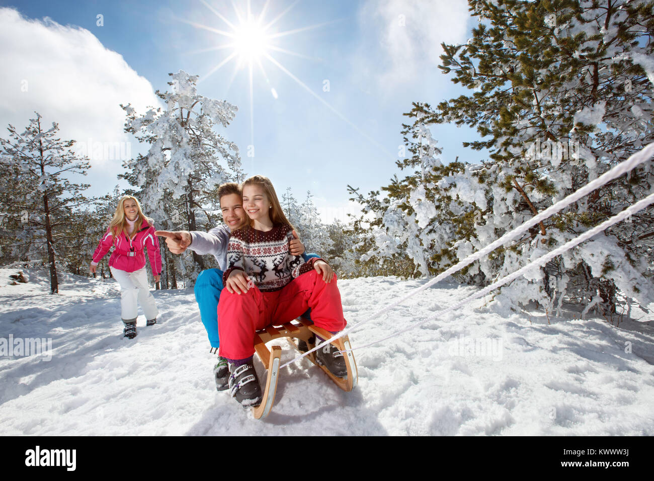Kinder genießen auf Schlitten auf Winterurlaub mit Mutter Stockfoto