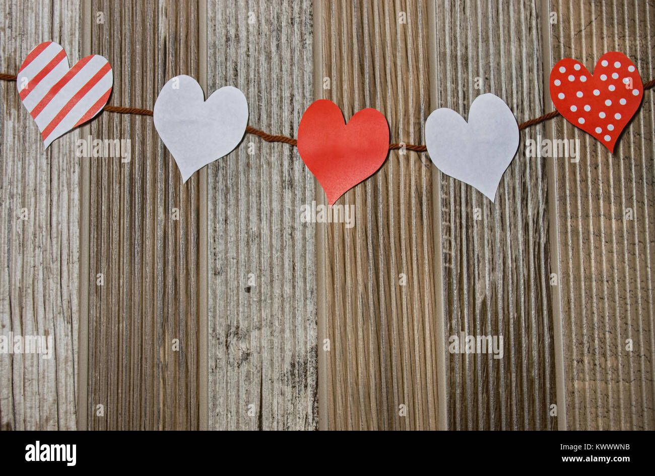 Rote und weiße Herzen hängen auf einer Linie vor Holz Stockfoto