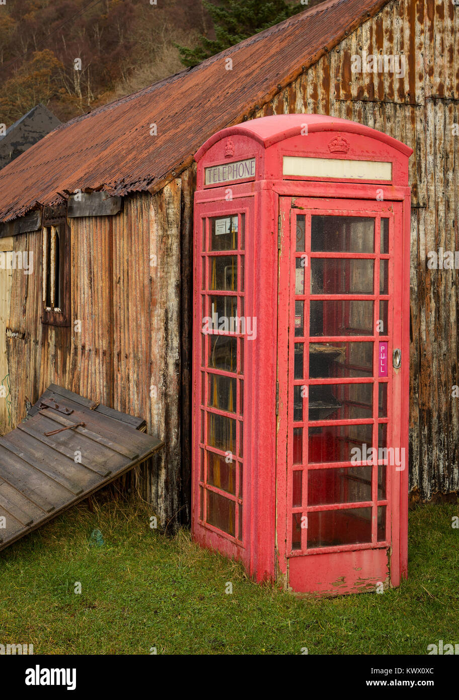 Eine alte legendäre rote Telefonzelle steht neben Rost Hütten im Dorf Diabaig in den Torridon Bereich der schottischen Highlands Stockfoto
