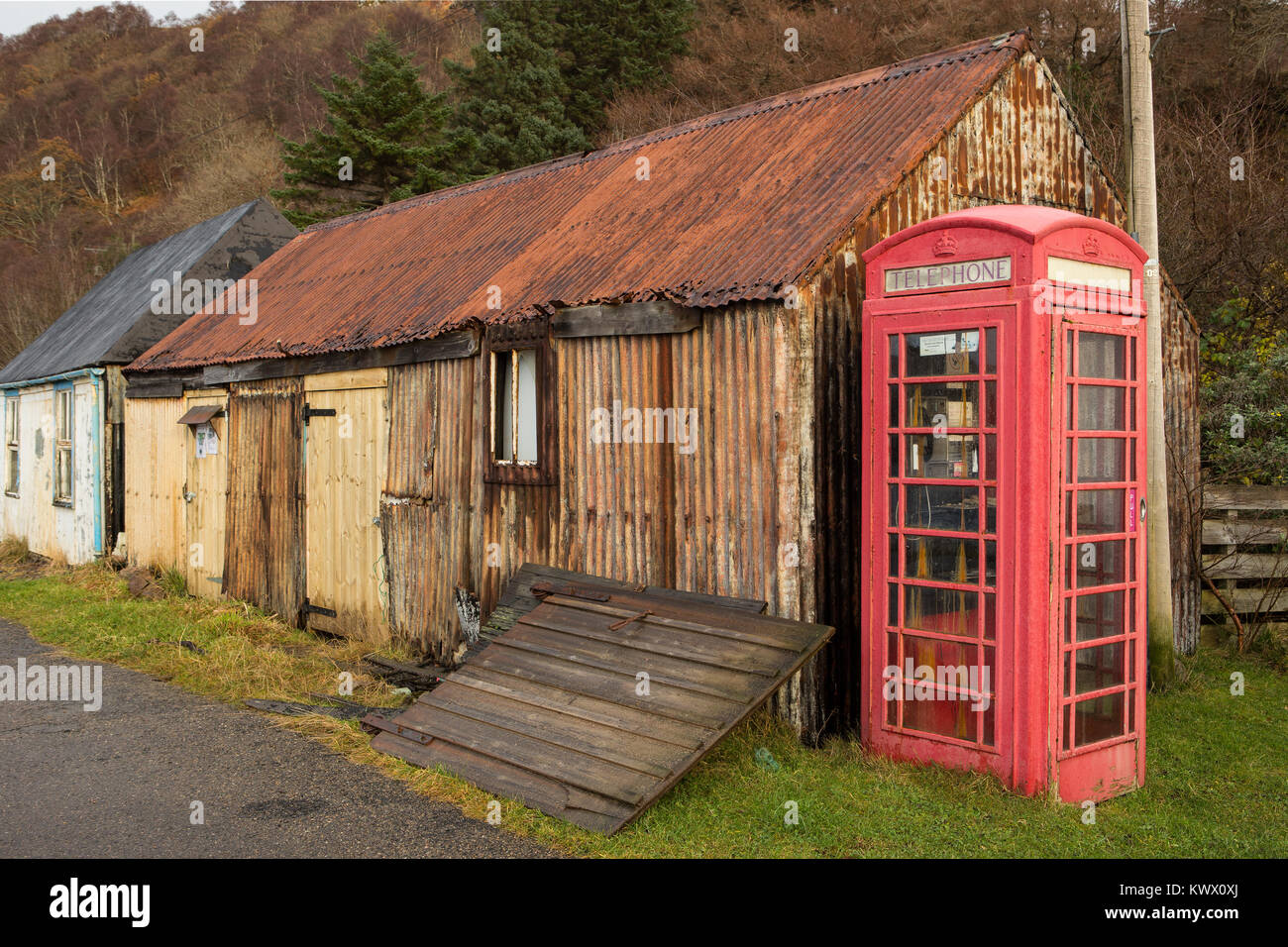 Eine alte legendäre rote Telefonzelle steht neben Rost Hütten im Dorf Diabaig in den Torridon Bereich der schottischen Highlands Stockfoto