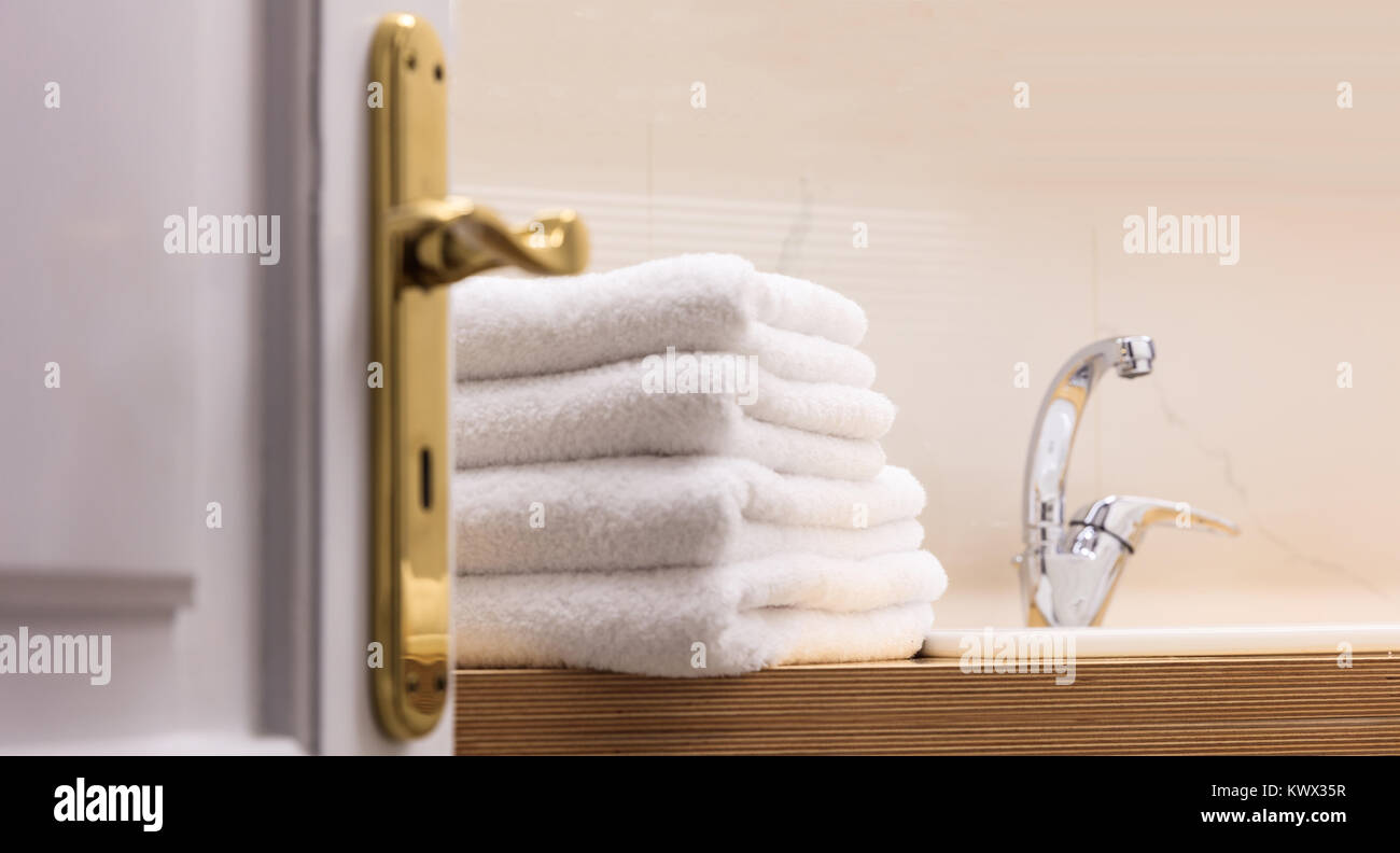 Hotel Bad von der offenen Tür. Weiße Handtücher auf Holz- Oberfläche gefaltet neben dem Waschbecken. Close Up. Stockfoto