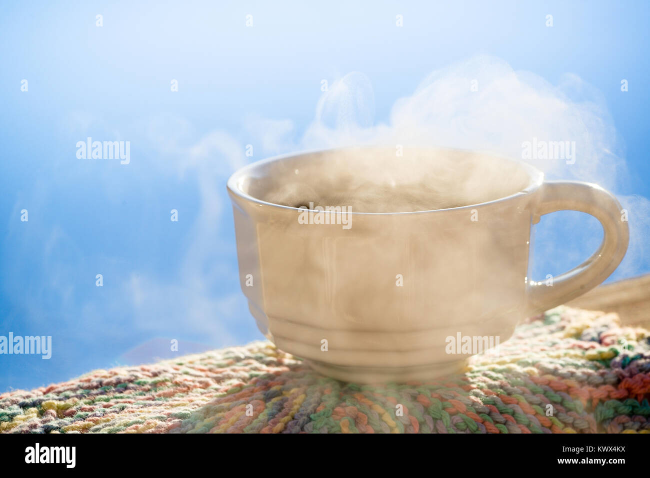 Bild horizontal Weiß antike Tasse schwarzen Kaffees sitzen auf Geländer mit Dampf. Blue Sky bunte Handgehäkelter Stück unter Tasse. Zimmer kopieren. Stockfoto