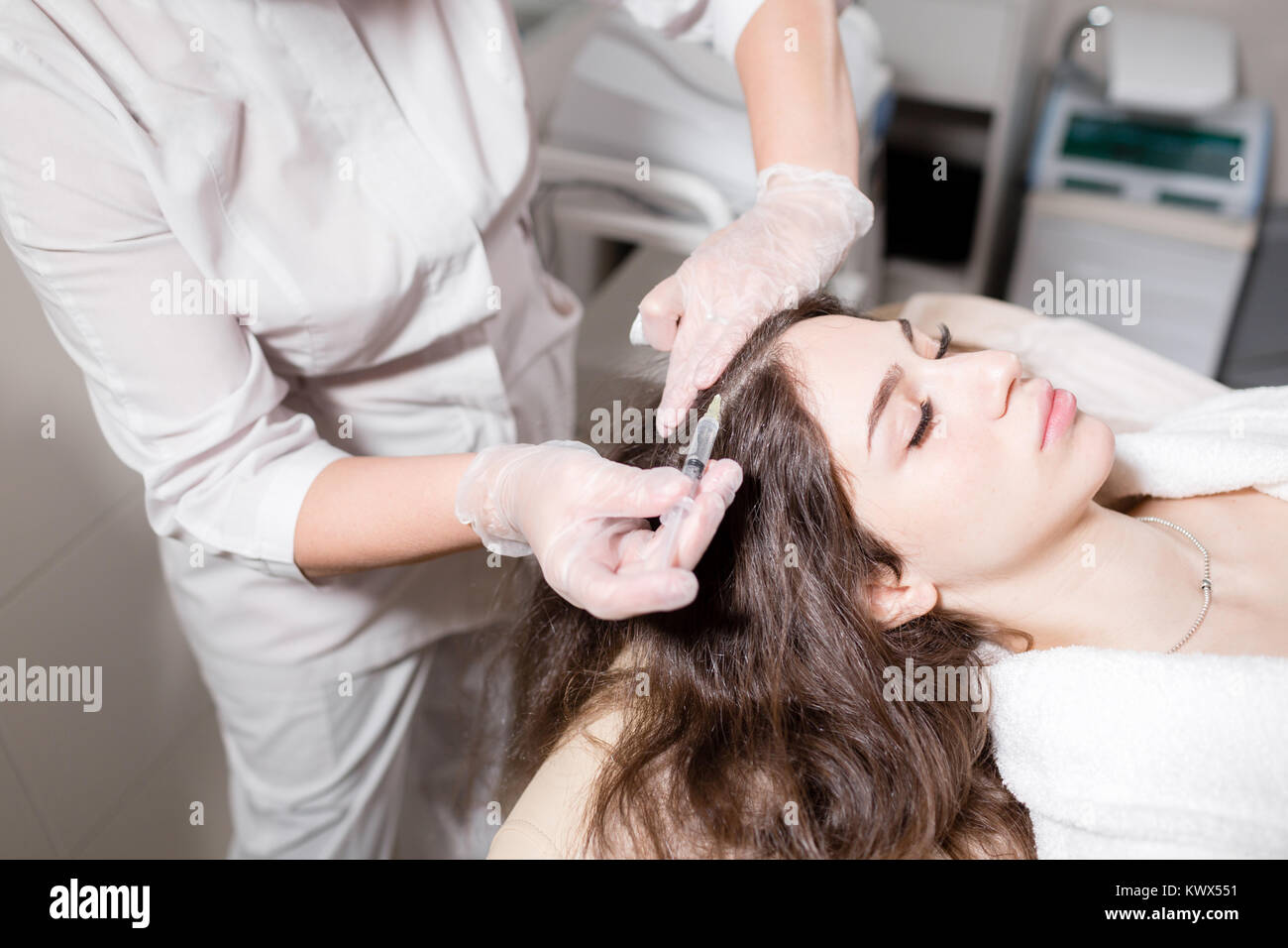 Stattliche Frau erhält eine Injektion in den Kopf. Das Verfahren macht Arzt in weiße Handschuhe. Das Konzept der Mesotherapie. Die Haare und ihr Wachstum zu stärken Stockfoto
