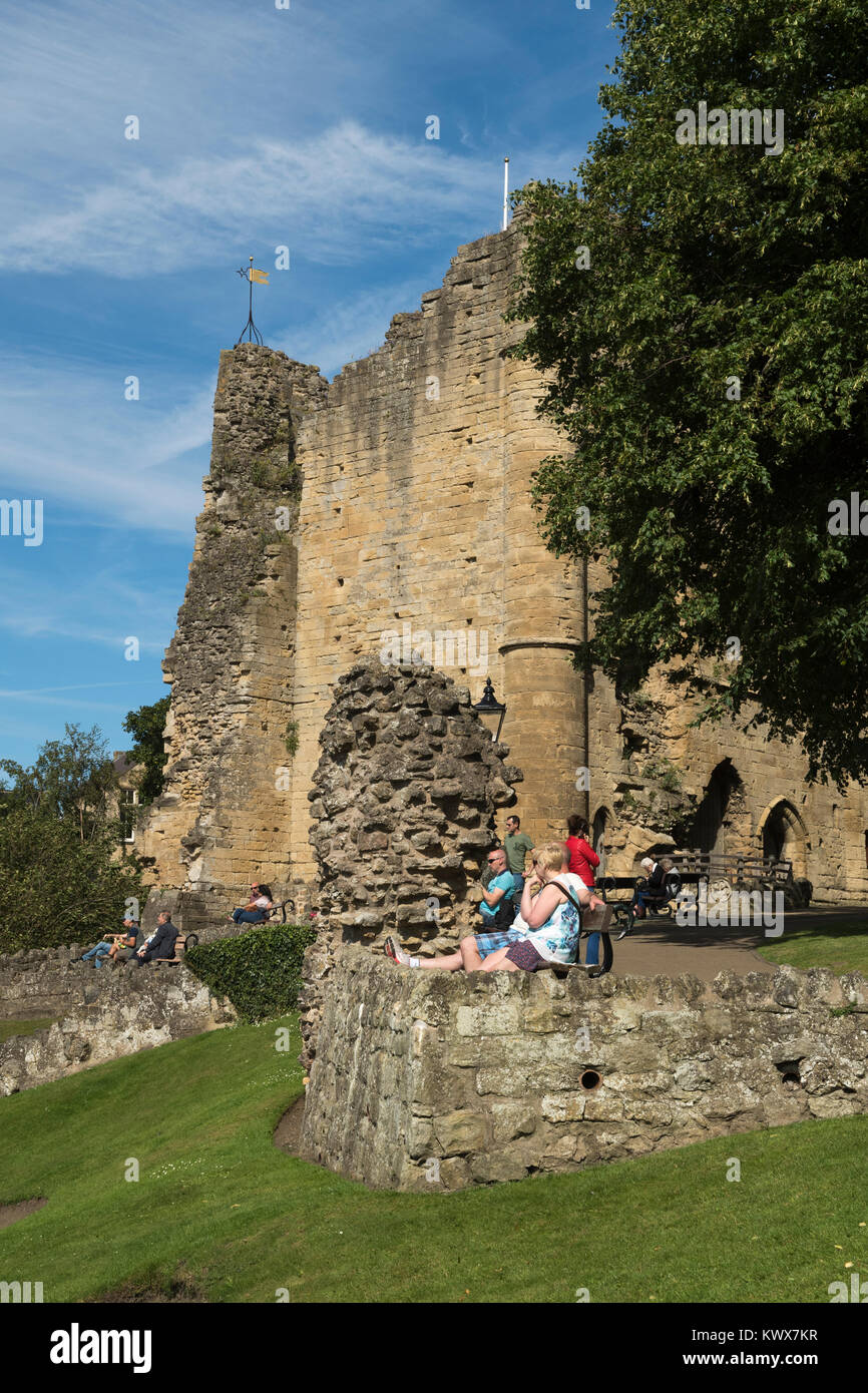 Leute sitzen auf Bänken Entspannen & Genießen Sommer Sonne, in der Nähe von mittelalterlichen Turm halten & Ruinen von knaresborough Schloss darüber hinaus - North Yorkshire, England, UK. Stockfoto