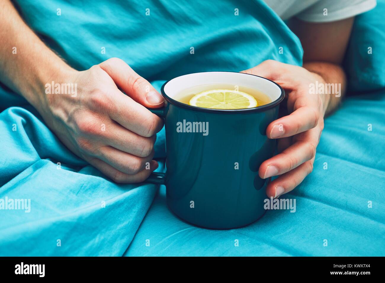 Grippesaison. Hand der kranken Mann mit Tasse der heißen Tee im Bett. Stockfoto