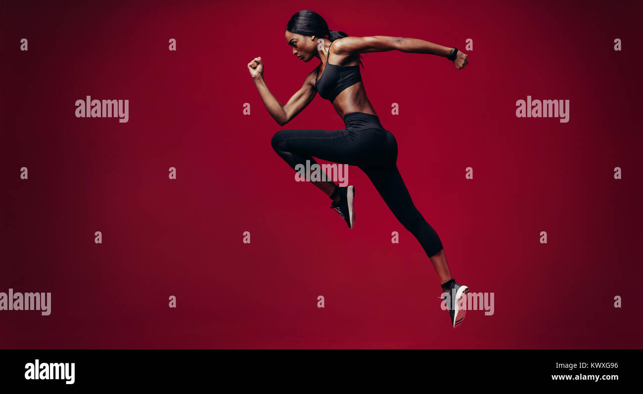 Sport Frau über den roten Hintergrund. Volle Länge geschossen von gesunden jungen afrikanischen Frau sprinten. Stockfoto