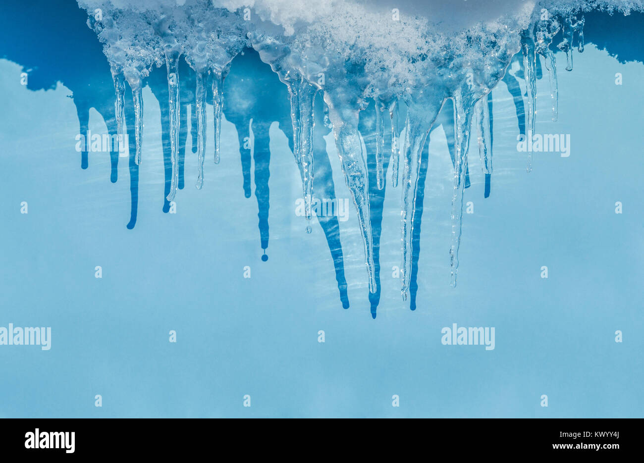 Winter Eiszapfen gebildet der schmelzende Schnee gegen pulsierenden blauen Hintergrund Stockfoto