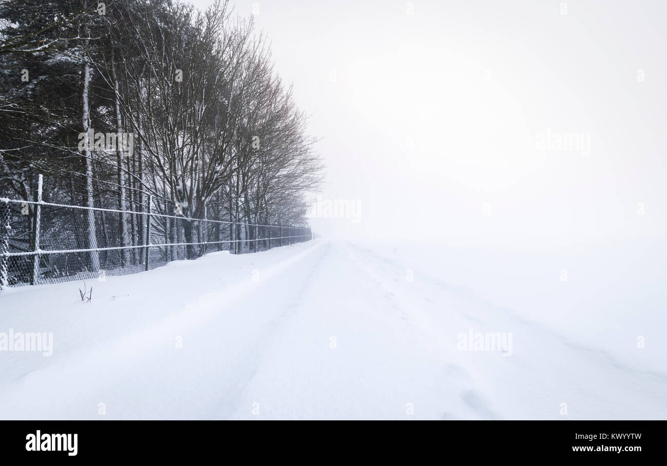 Landstraße bei starkem Schneefall im Winter dunstige Tag abgedeckt Stockfoto