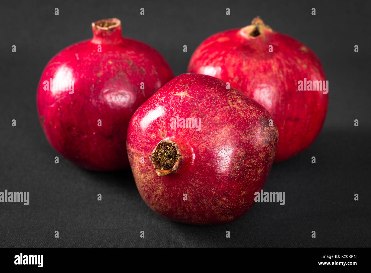 Drei reife Granatäpfel auf schwarzem Hintergrund Stockfoto