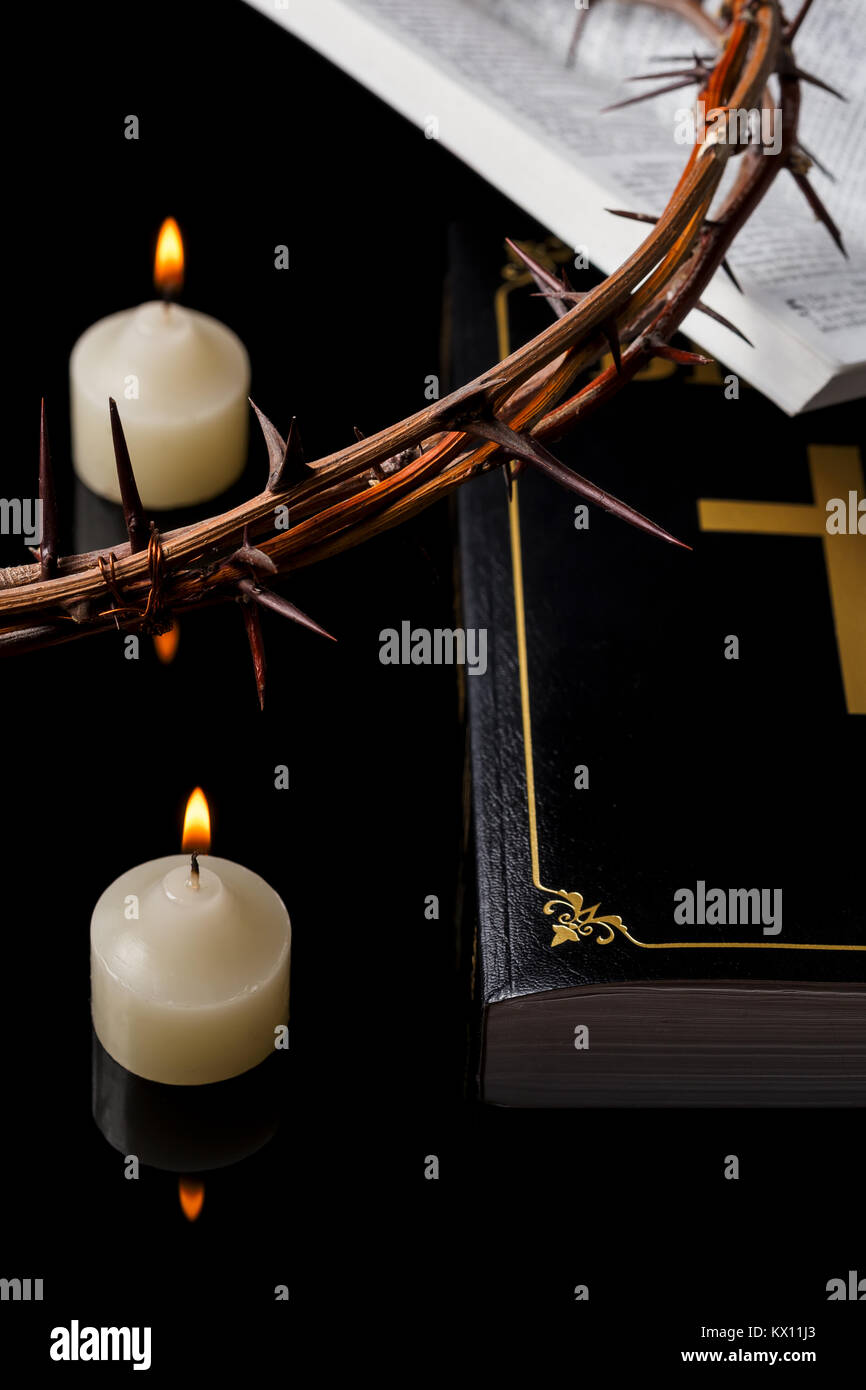 Kerzen mit Dornenkrone und Heilige Schrift auf schwarzem Hintergrund. Stockfoto