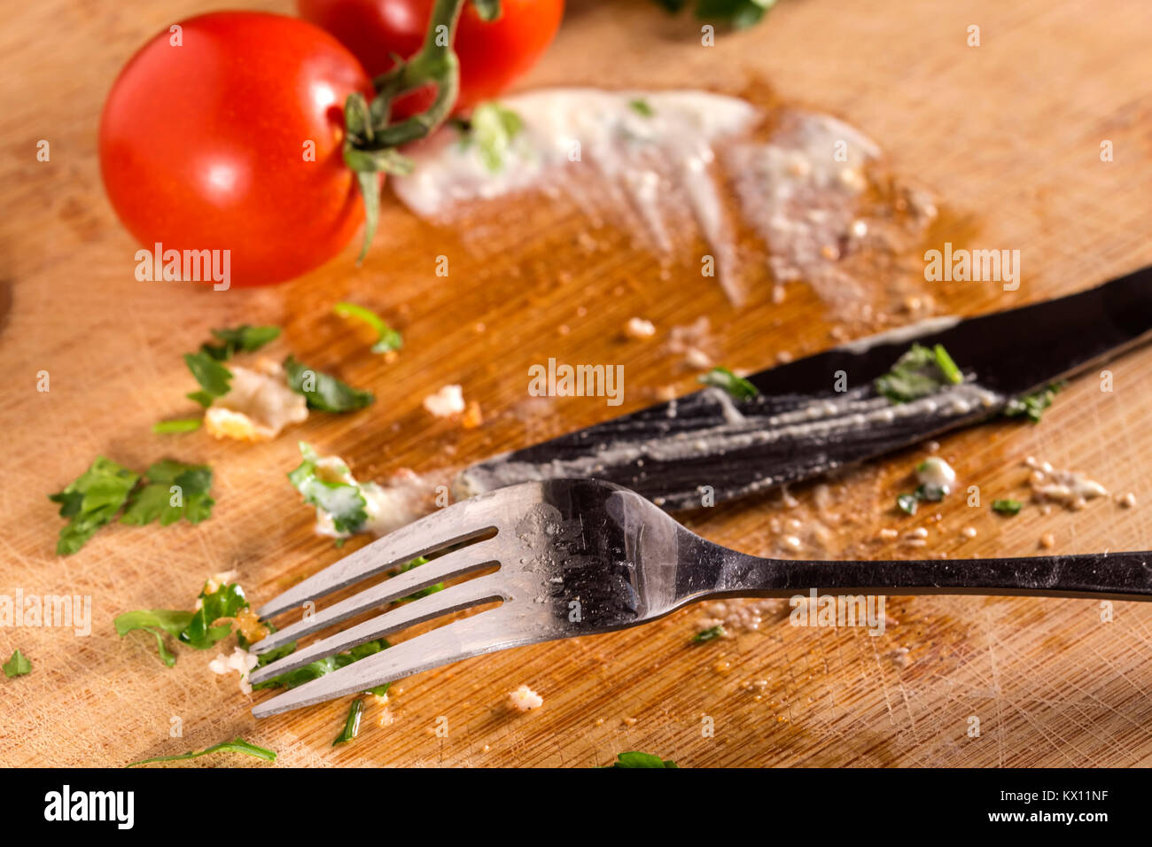 Schmutziges Geschirr auf Holz- Oberfläche mit Kirschtomaten, weiße Sauce und Petersilie Stockfoto