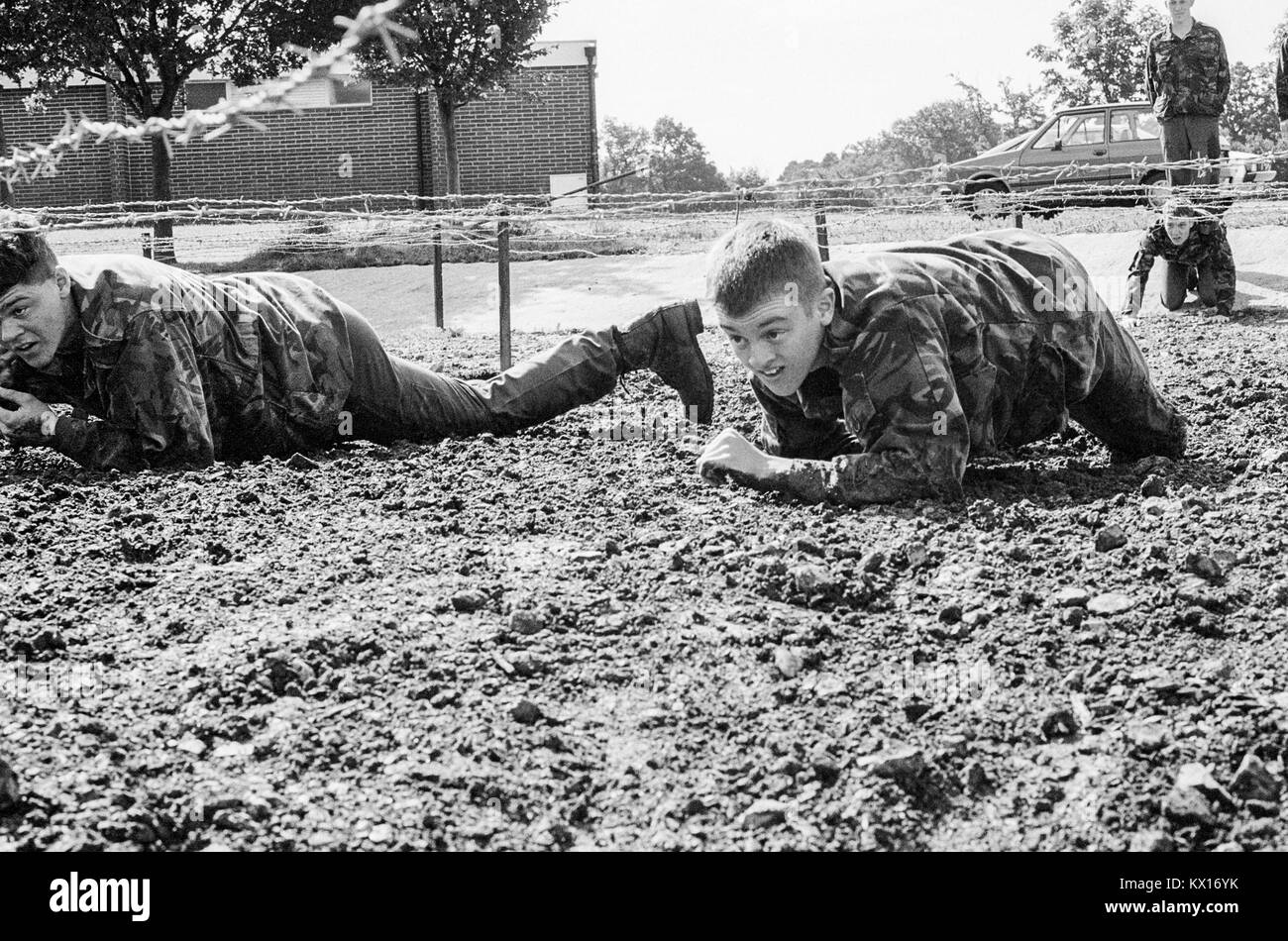 Britische Armee squaddies in der Ausbildung durch Schlamm kriechen unter Stacheldraht als Teil eines Hindernisparcours. England. 15. Juni 1993 Stockfoto